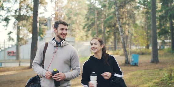 Couple walking outdoors with gym bags and water bottles