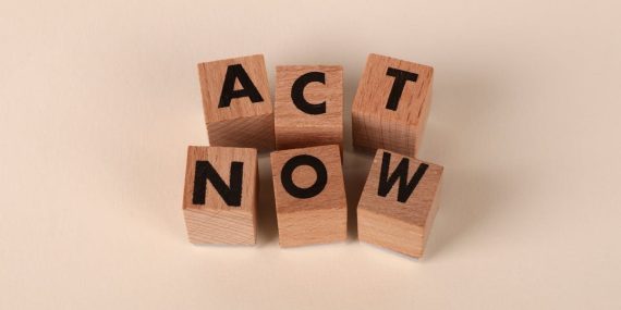 Wooden blocks with letters spelling 'ACT NOW', promoting urgency and motivation.